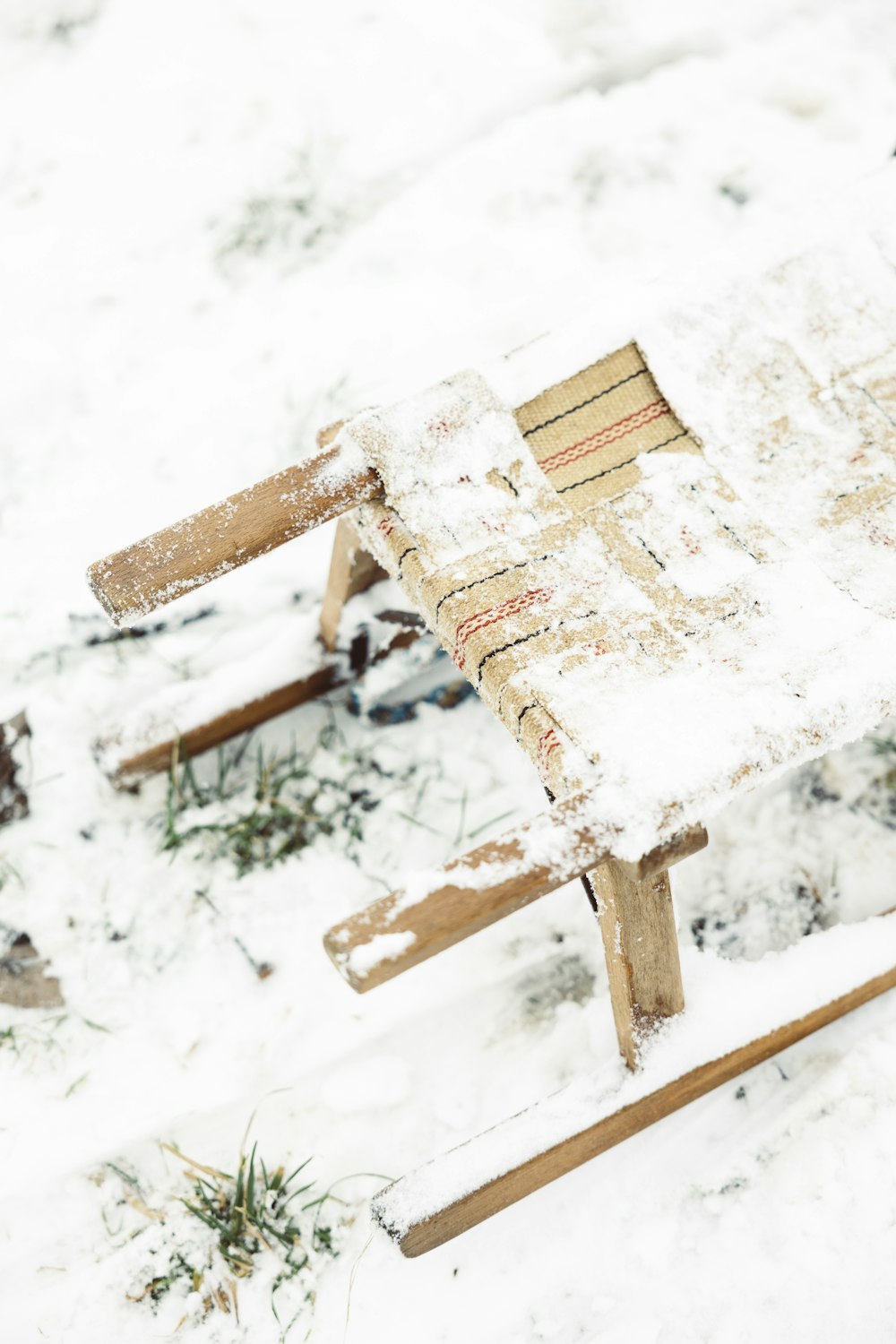 uma cadeira de madeira sentada no chão coberto de neve