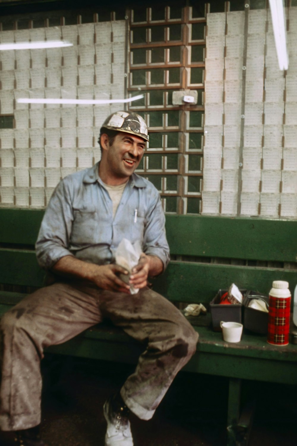 a man sitting on a green bench holding a drink