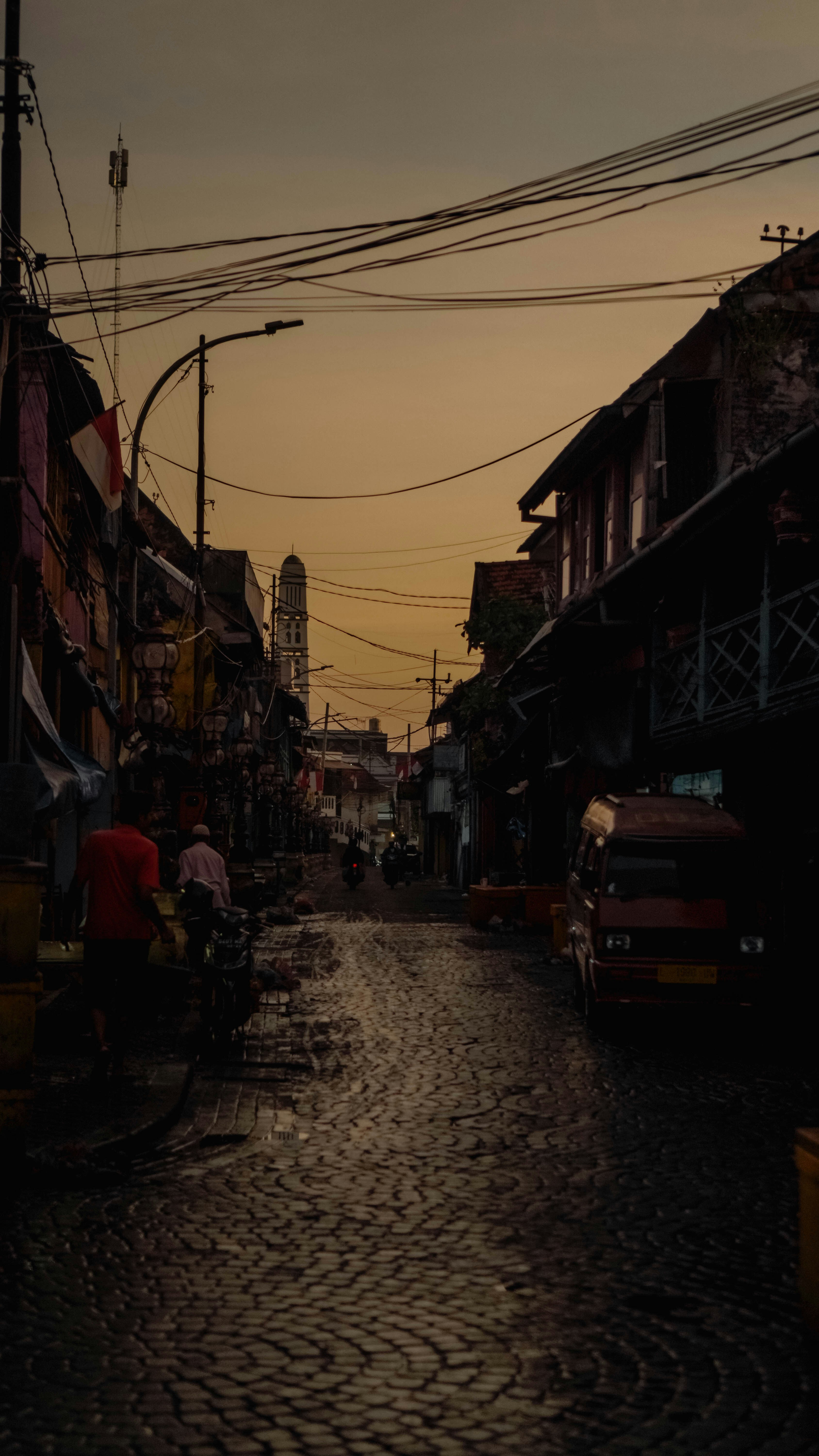 a cobblestone street with a few people walking down it