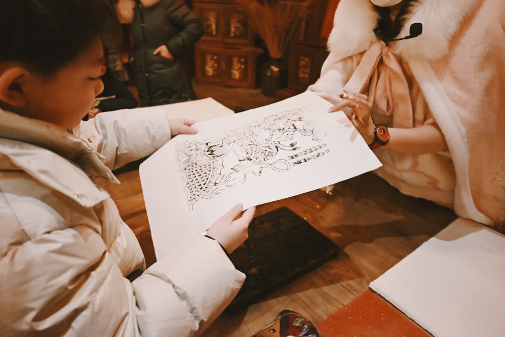 a person sitting on the floor with a drawing on a piece of paper