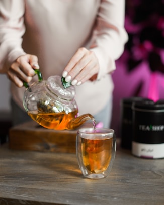 a woman pouring tea into a glass cup