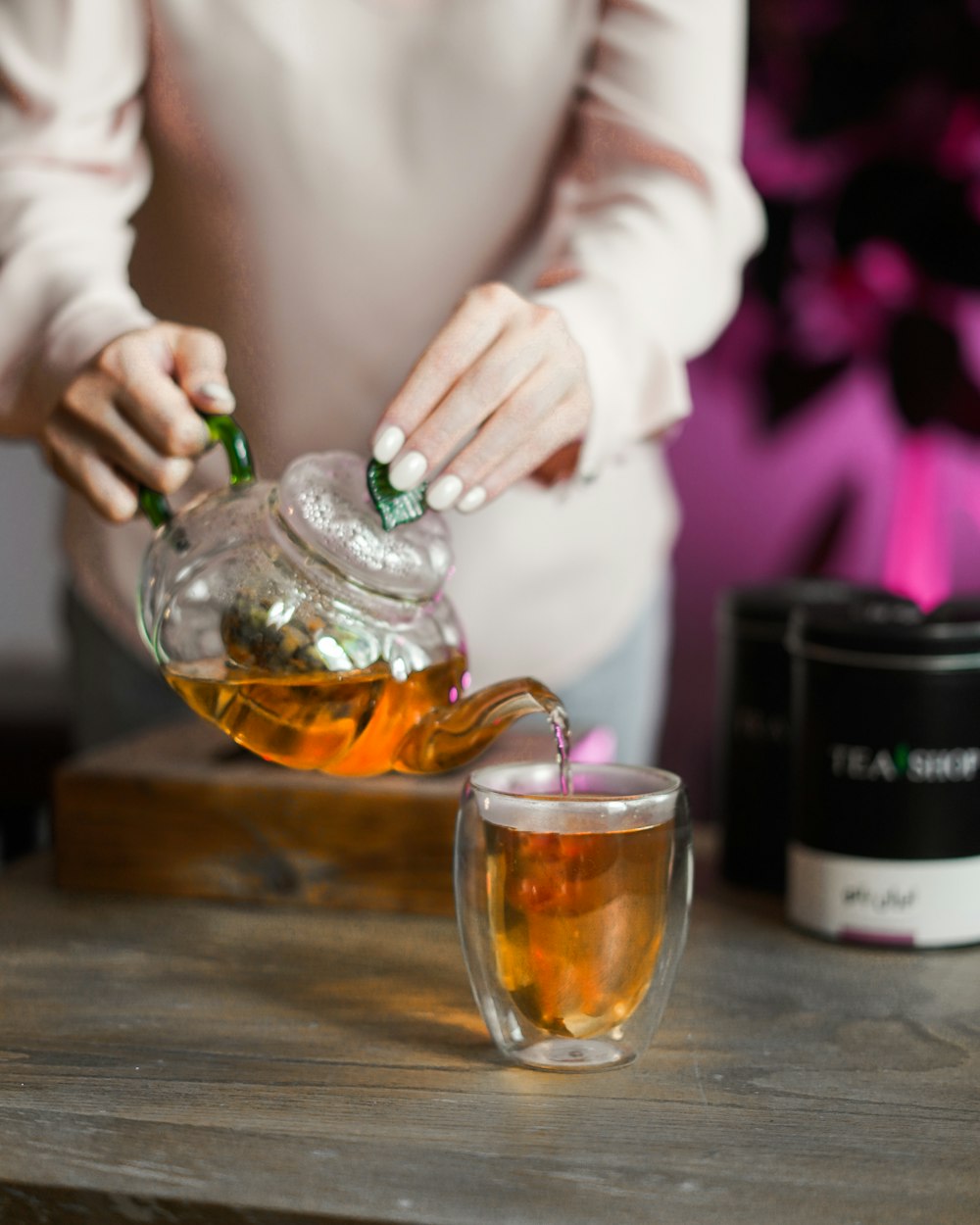 a woman pouring tea into a glass cup