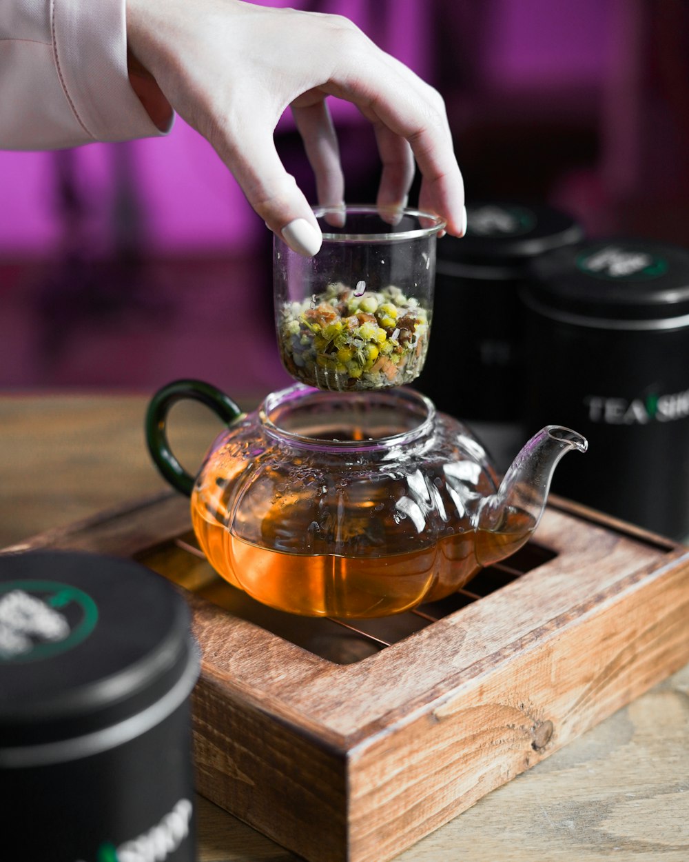 a person is putting food in a glass teapot