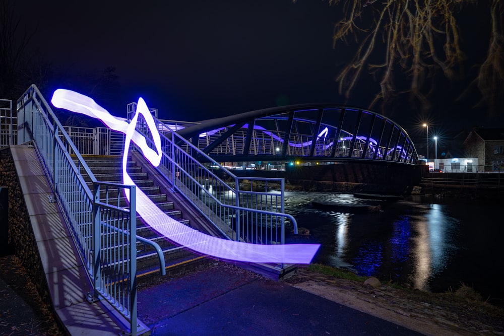 a metal railing next to a river at night