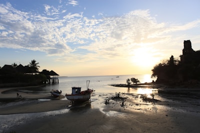 Peaceful Haitian coastal scene with boats and sunset hues.