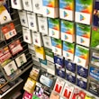A display rack featuring a variety of gift and prepaid cards from popular brands. Cards are organized in stacks and rows, including Google Play, Apple iTunes, Amazon, PlayStation, Netflix, and more. The colors are vibrant and the packaging is clearly branded.