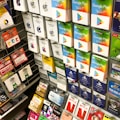 A display rack featuring a variety of gift and prepaid cards from popular brands. Cards are organized in stacks and rows, including Google Play, Apple iTunes, Amazon, PlayStation, Netflix, and more. The colors are vibrant and the packaging is clearly branded.