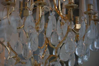Close-up of a shimmering gold chandelier casting soft glows over a sleek modern banquet table.