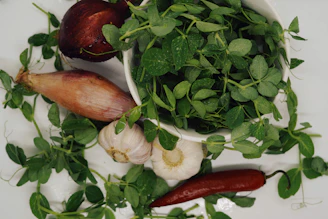Fresh vegetables and herbs arranged next to a bottle of seh enhancer on a clean white countertop.