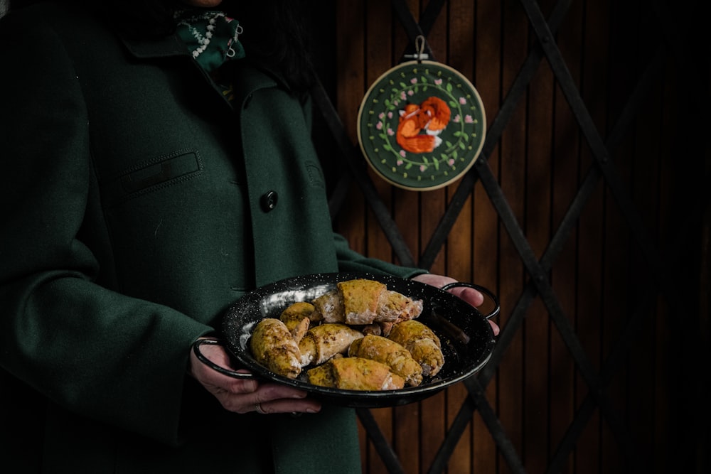 a person in a green coat holding a plate of food