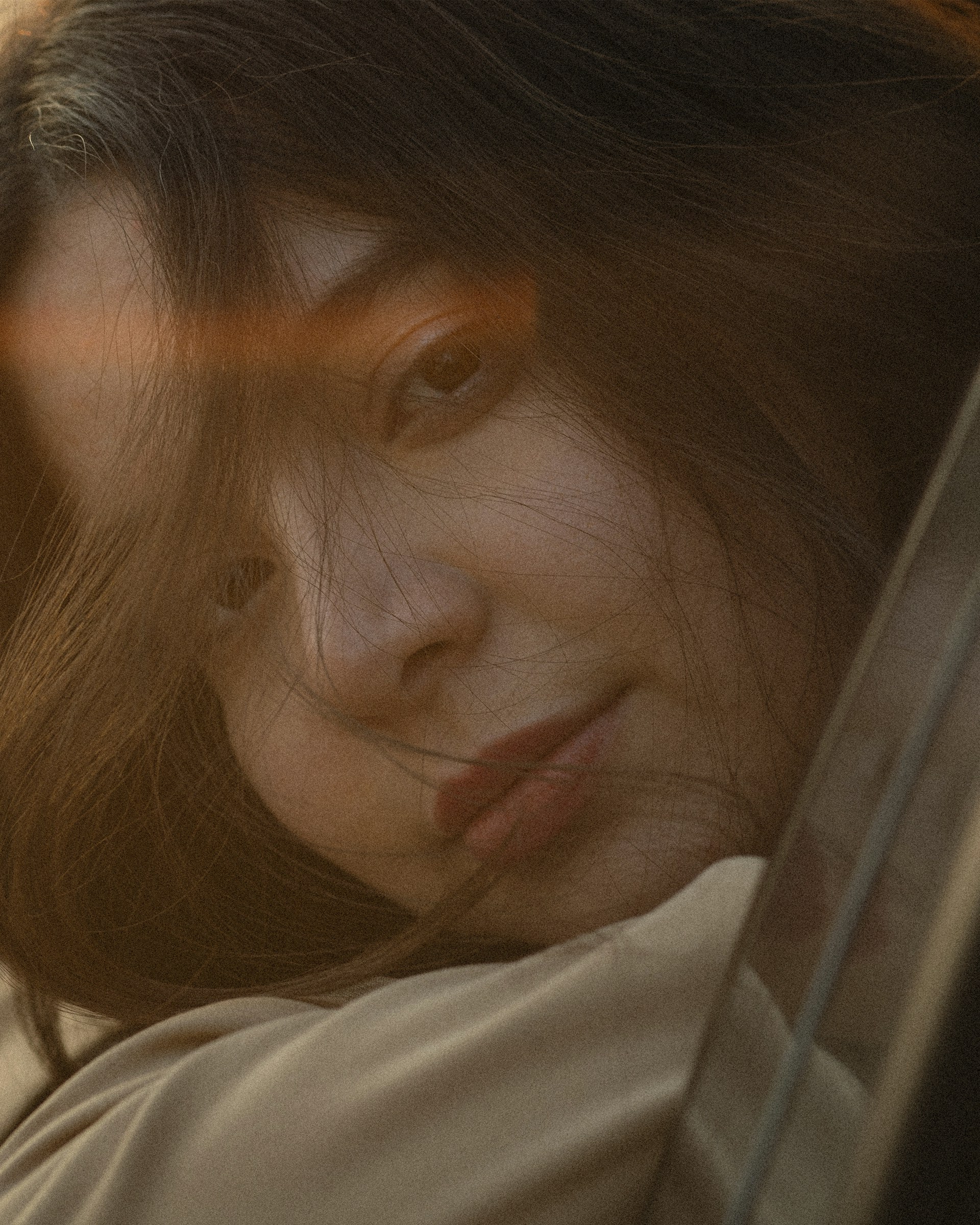 A close-up frame from a heartfelt documentary, showing a subject's expressive face illuminated by soft natural light.