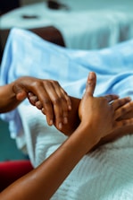 a person holding another person's hand in a hospital bed