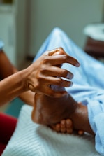 a person holding the hand of another person in a hospital bed