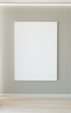 A minimalist white-walled gallery corner featuring a large abstract canvas with soft natural light streaming through tall windows.