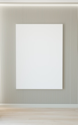 A minimalist interior featuring a large blank white canvas on a wall with vertical grooves. The floor is wooden, and there's soft lighting from above.