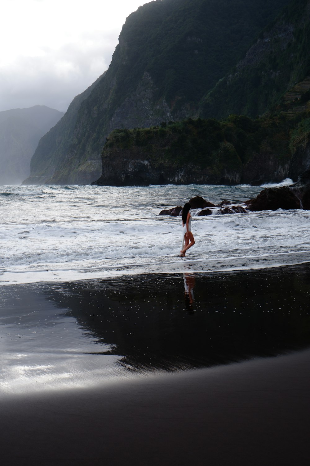 a woman standing on top of a beach next to the ocean