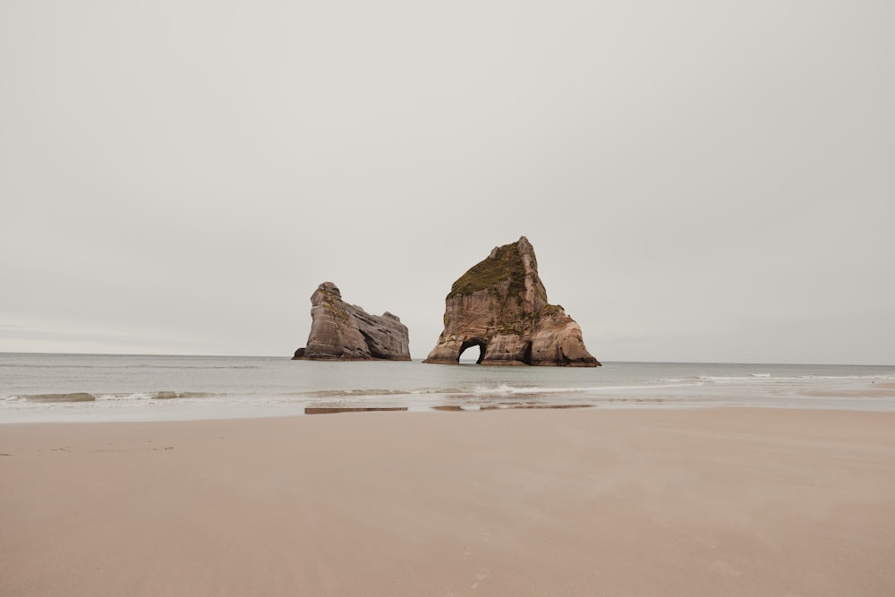 a rock formation on a beach near the ocean