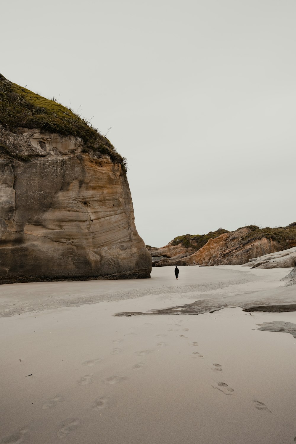 a person walking on a beach next to a cliff