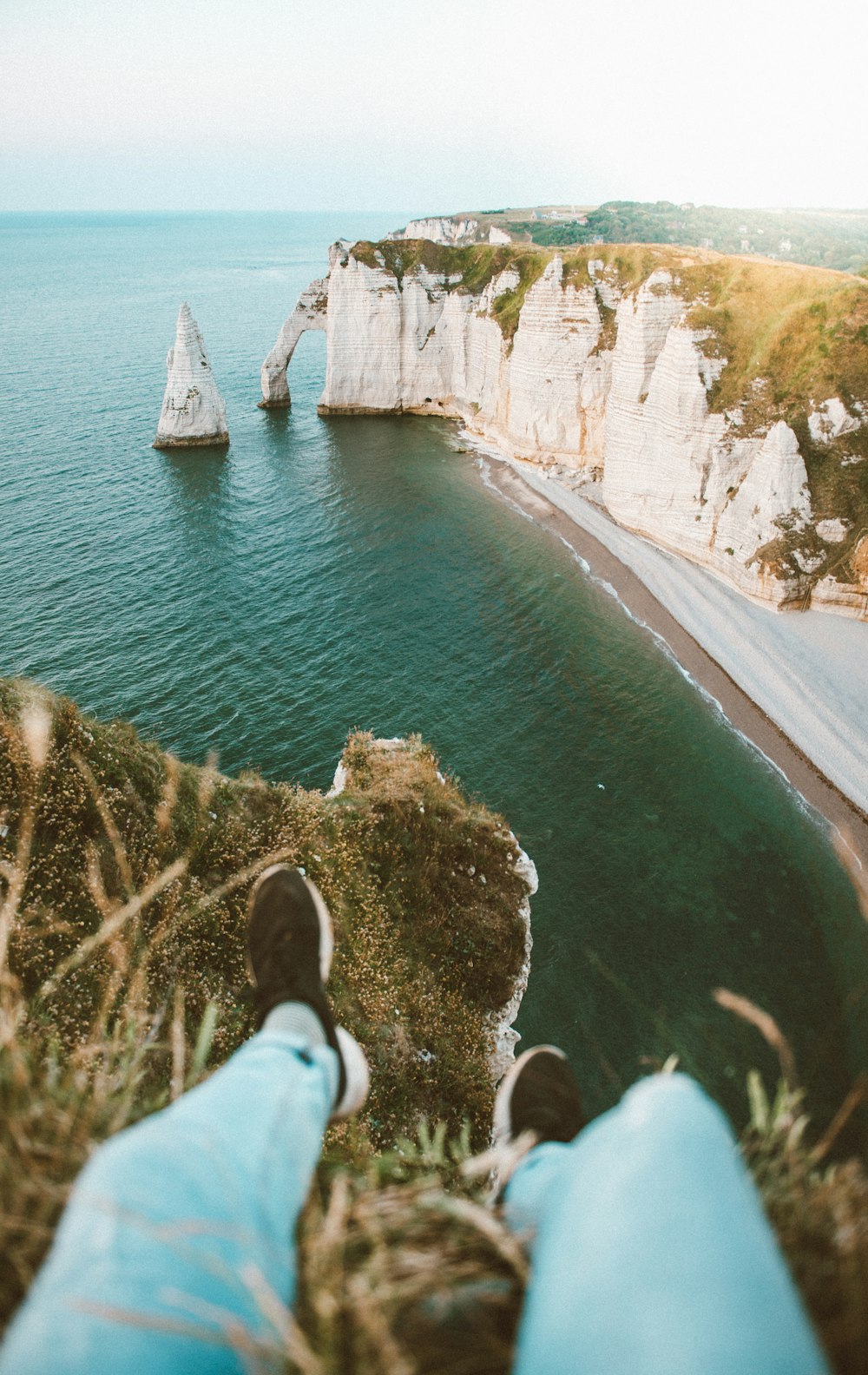 a person's feet resting on the edge of a cliff overlooking the ocean