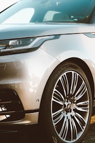 A side view of a sleek car with gleaming rims and perfectly waxed paint under natural light.