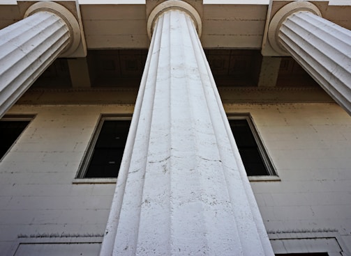 a tall white building with two windows and two columns