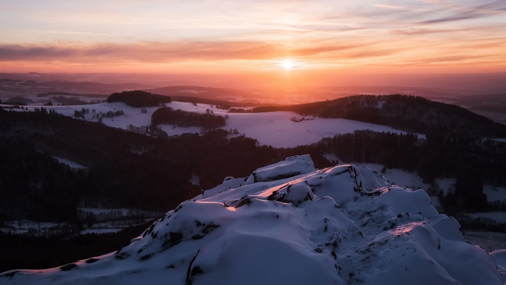 the sun is setting over a snowy mountain