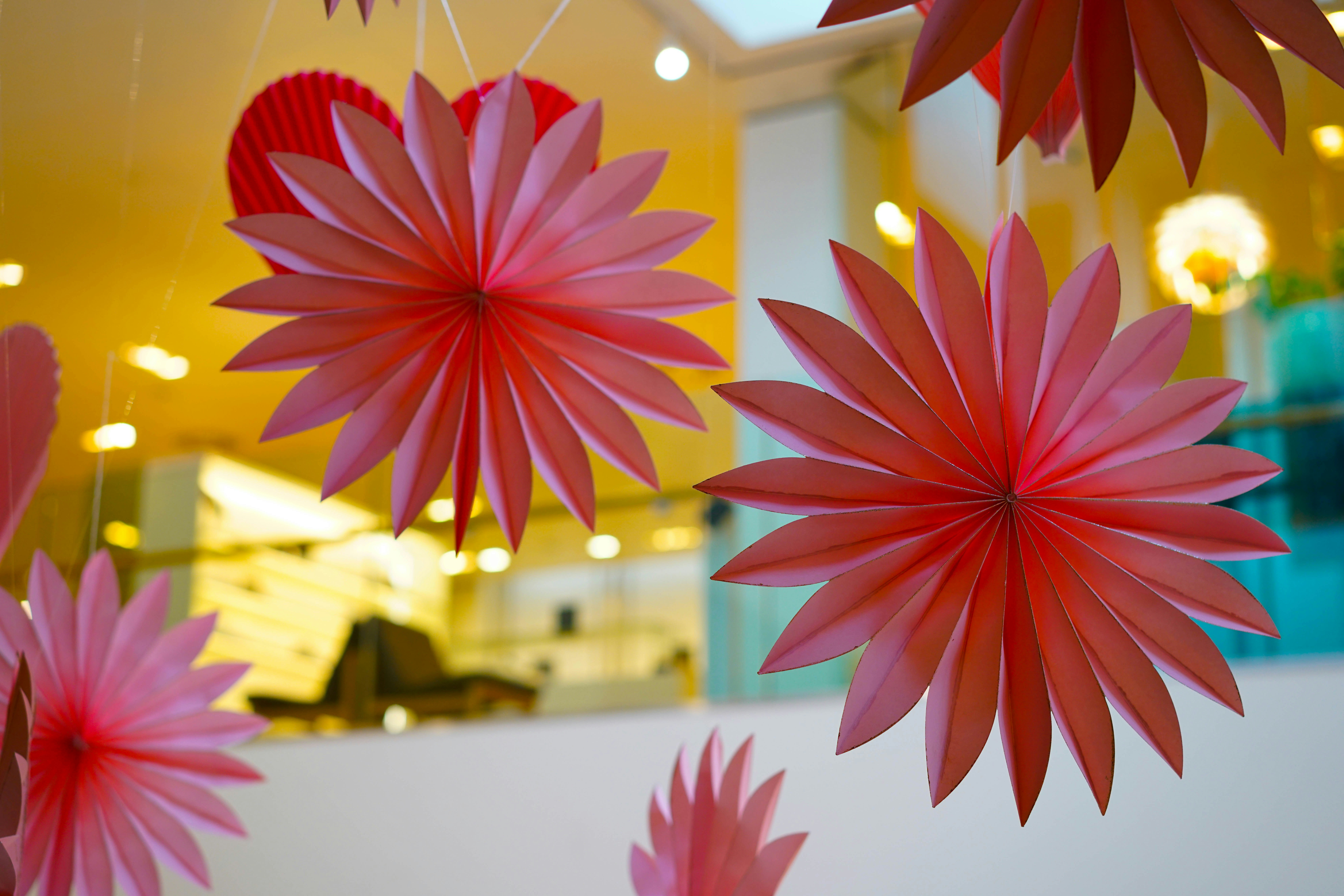 a group of red paper flowers hanging from a ceiling