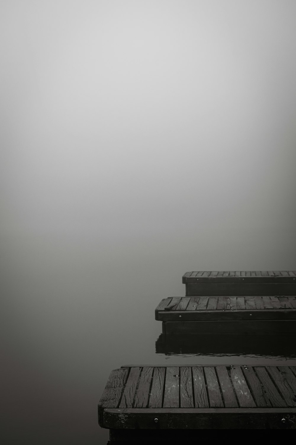 a black and white photo of a dock on a foggy day