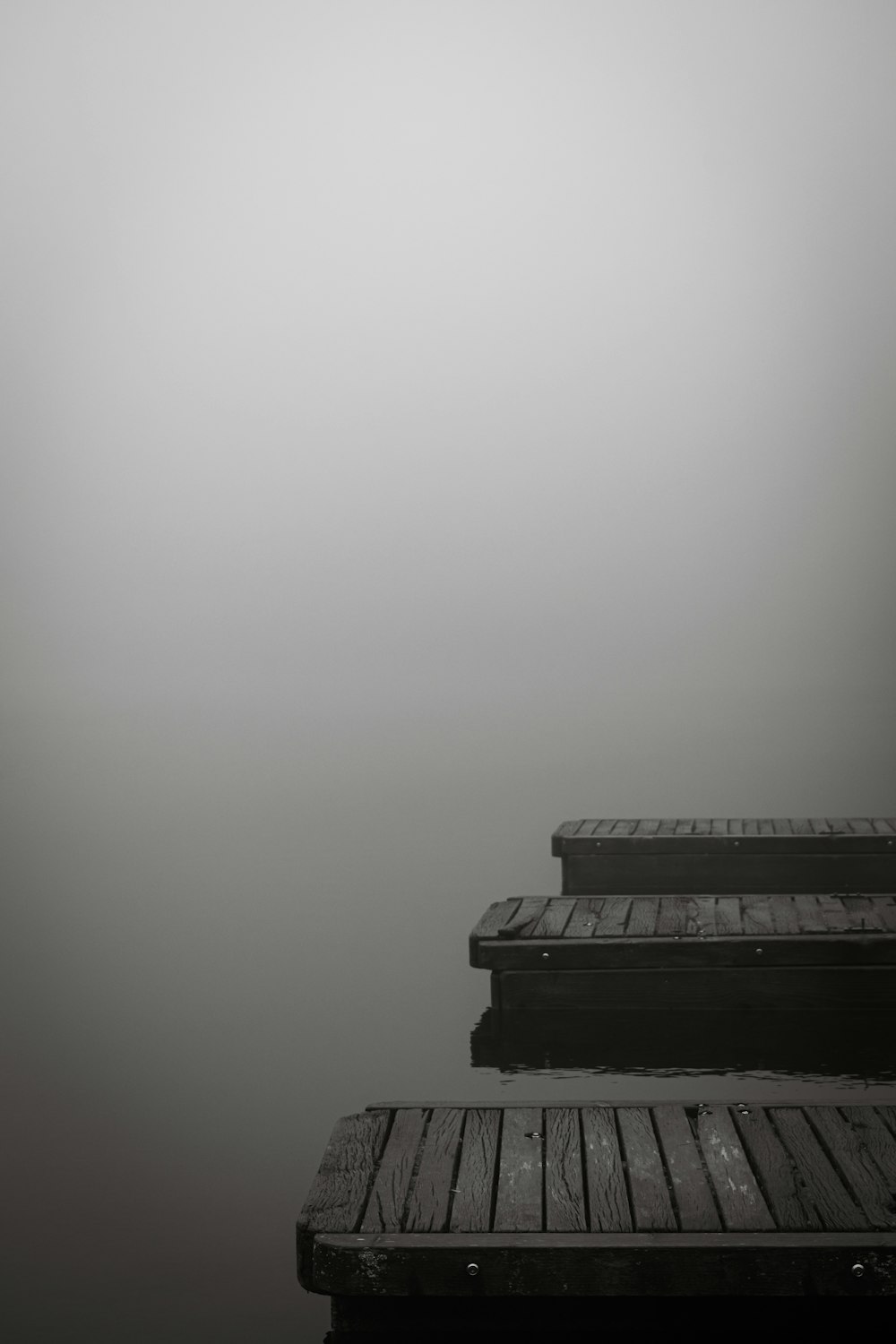 Una foto en blanco y negro de un muelle en un día de niebla