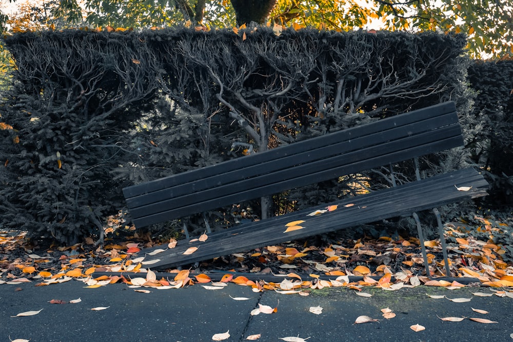a wooden bench sitting in the middle of a pile of leaves