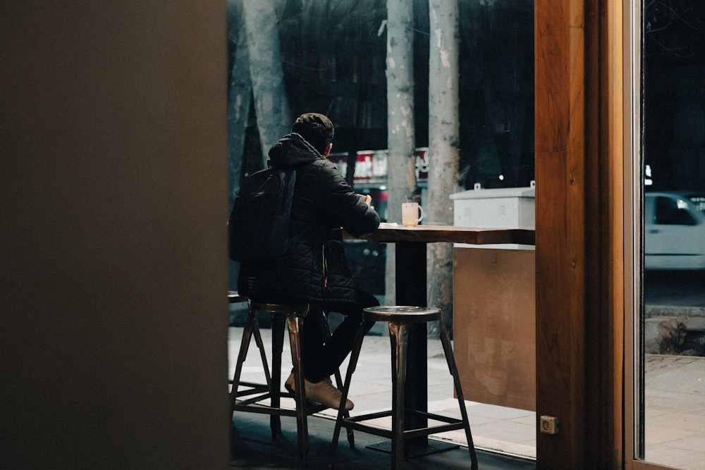 a person sitting at a table in front of a window