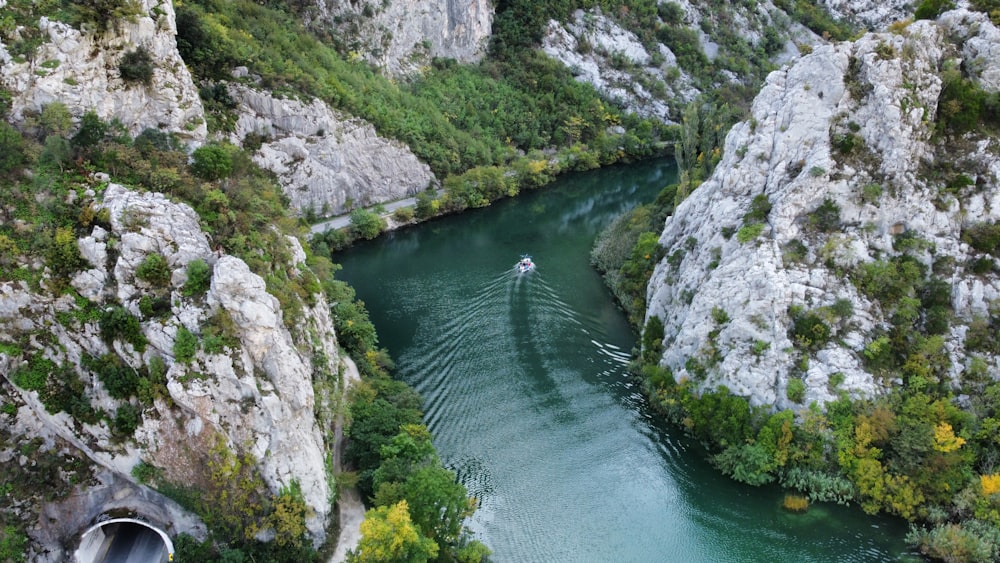 a boat traveling down a river surrounded by mountains