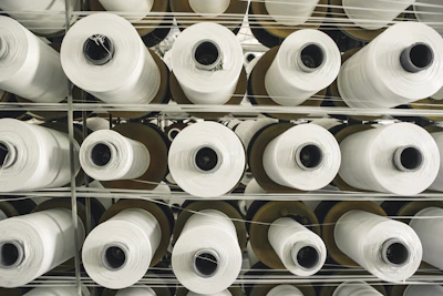 Close-up of textured grey fabric rolls stacked neatly in a factory setting.