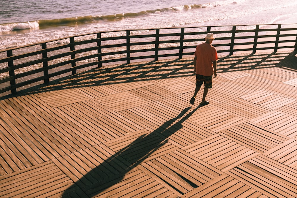 a man standing on a wooden deck next to the ocean