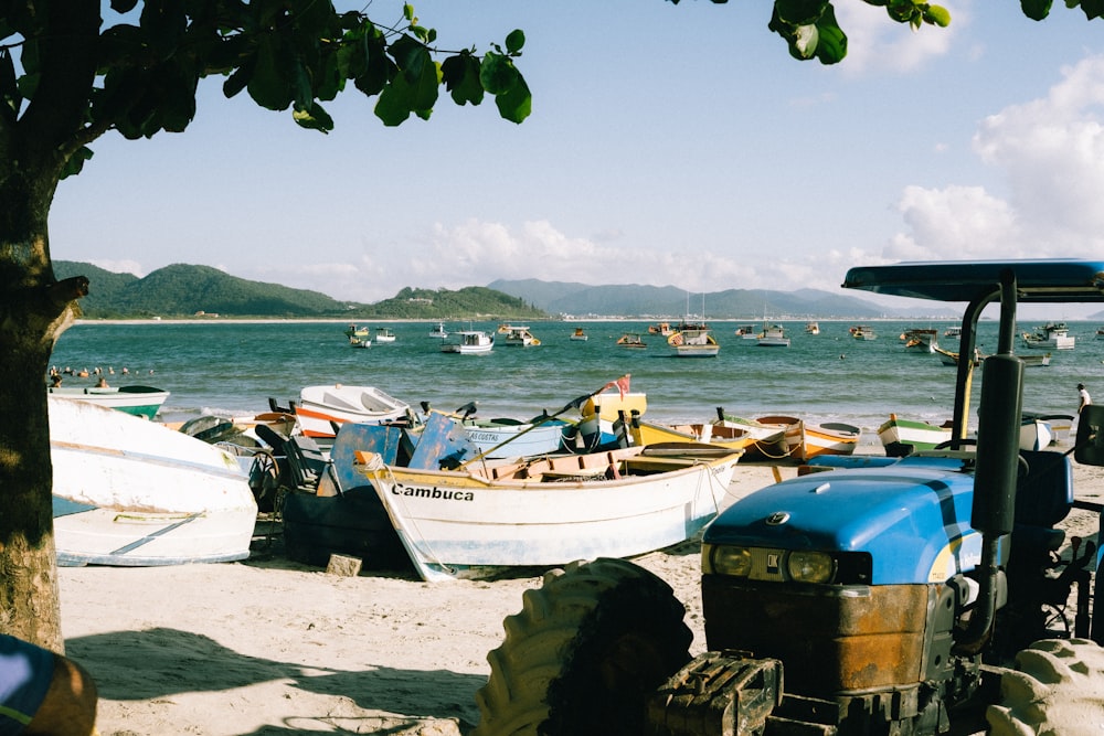 a tractor parked on a beach next to boats