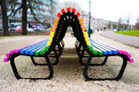 A colorful painted bench with a backrest, set on a playground area.