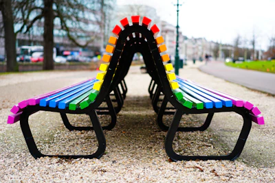 A colorful painted bench with a backrest, set on a playground area.
