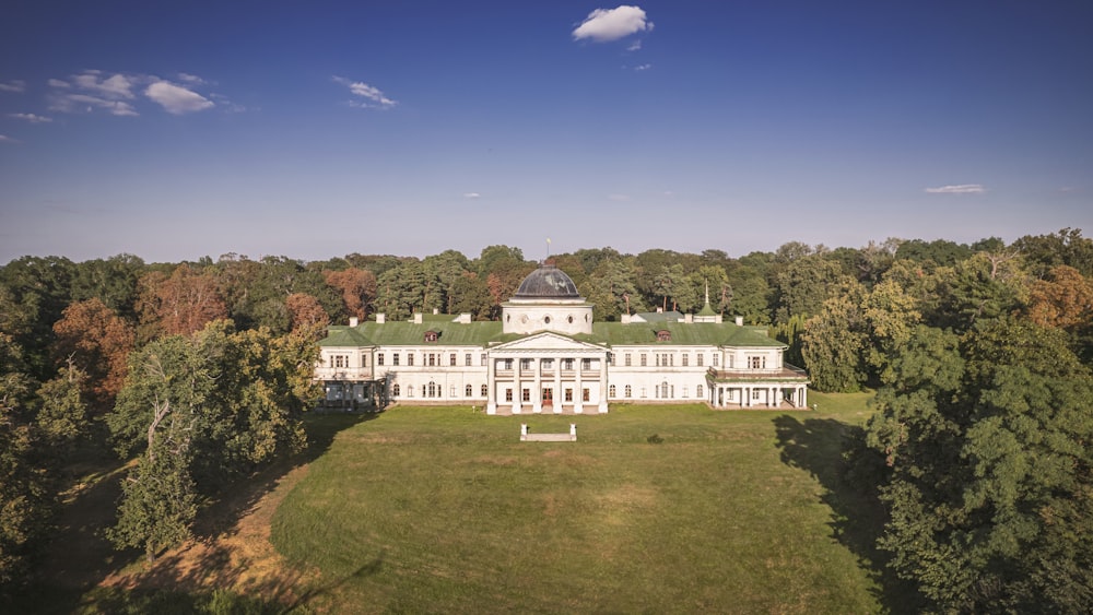 an aerial view of a large white house surrounded by trees