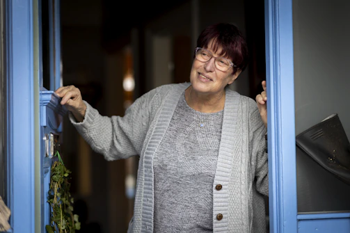 a woman is opening a blue door and smiling