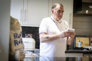 A friendly plumber answering a phone call in a bright, modern kitchen.