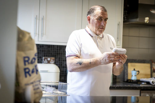 A friendly plumber answering a phone call in a bright, modern kitchen.