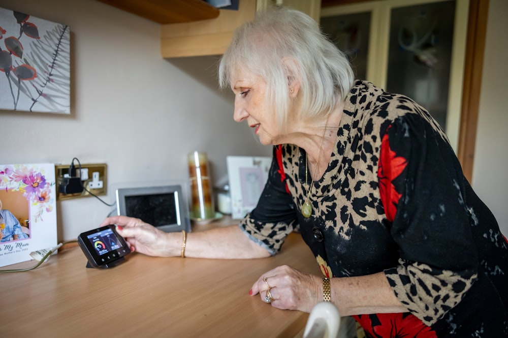 an older woman looking at a cell phone on a table