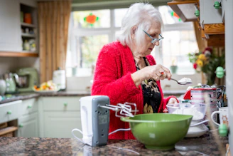 A smiling older woman preparing a colorful, nutritious meal in a bright kitchen.