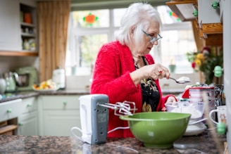 A warm, inviting kitchen scene with a mature woman over 40 preparing a colorful, healthy meal.
