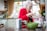 A smiling elderly woman holding a grocery bag in a cozy kitchen.