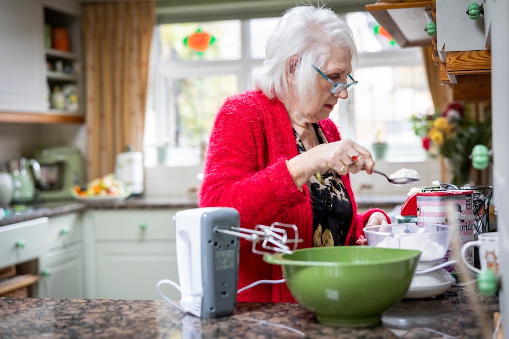 Eine Frau in einer roten Jacke bereitet Essen in einer Küche zu