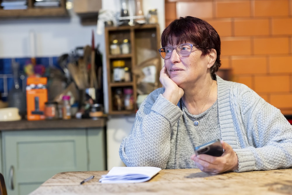 a woman sitting at a table with a cell phone