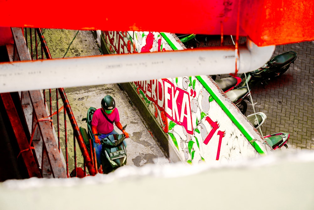 a man riding a motorcycle down a street next to a red and white sign