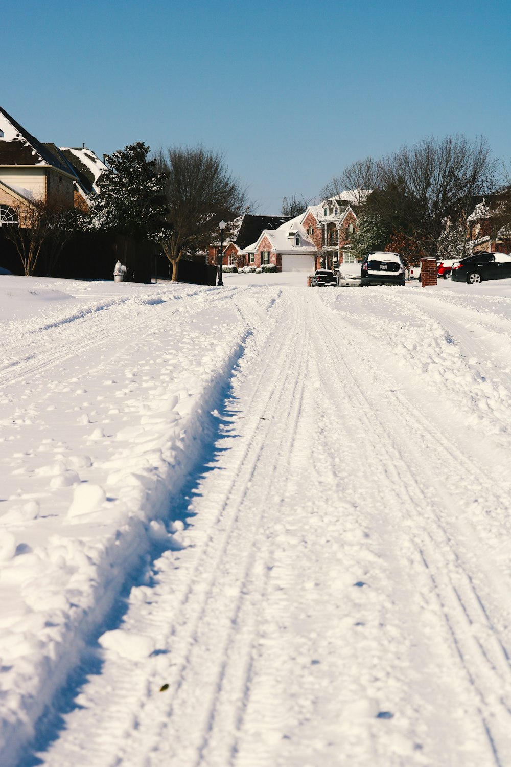 a snow covered street with houses in the background