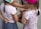 A group of children are standing close together, engaging in an activity. They are wearing colorful clothes and hats, and their arms are intertwined, indicating playfulness or a game.